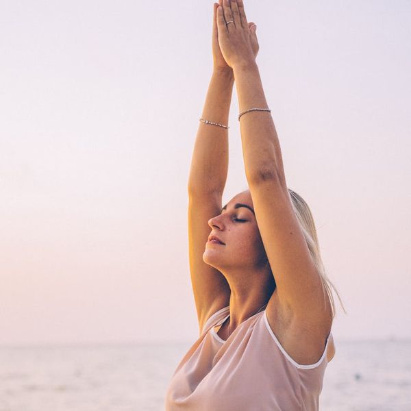 Person feeling energized and stretching outdoors during sunrise.